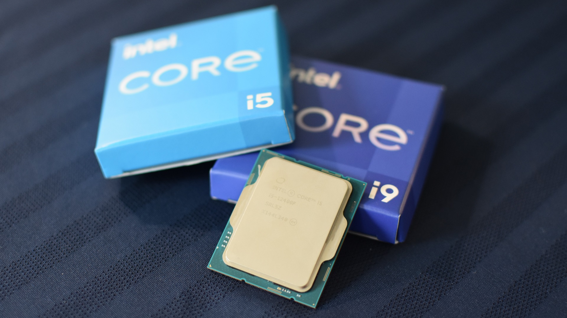 An Intel Core i5-12400F CPU next to to some Intel Core i5 and Core i9 boxes.