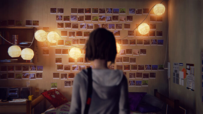 Life Is Strange protagonist Max Caulfield faces her polaroid photo wall, which is softly illuminated by a string of hanging lights.