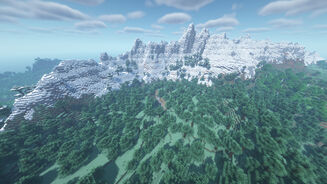 A massive snowcapped mountain range in Minecraft, surrounded by forest.