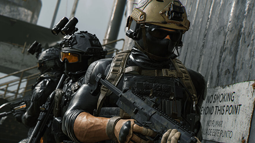 Three soldiers in Modern Warfare 2 carrying rifles wait by a wall outside.